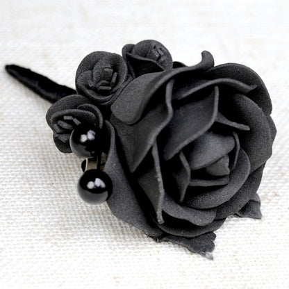 a close up of a black rose on a white surface