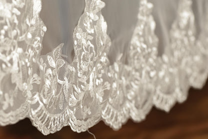 A close-up view of a delicate, white lace fabric with intricate floral patterns.
