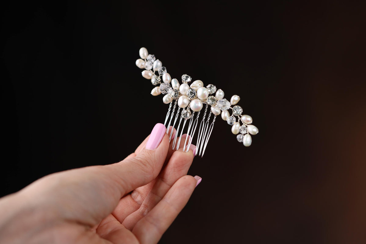 a woman's hand holding a comb with pearls on it