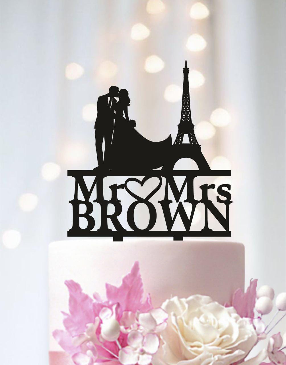 A black silhouette of a bride and groom on top of a wedding cake, with the words "Mr. Brown" and "Mrs. Brown" written on the cake topper.