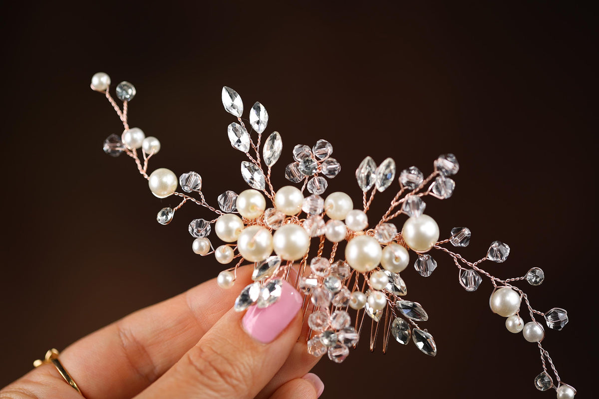 a hand holding a crystal and pearl hair comb