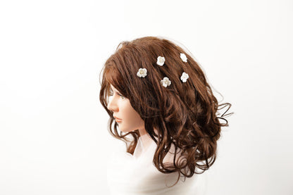 A mannequin head with long, curly brown hair adorned with small white flowers.
