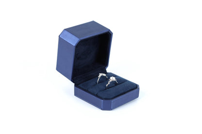 A blue jewelry box containing two diamond engagement rings.