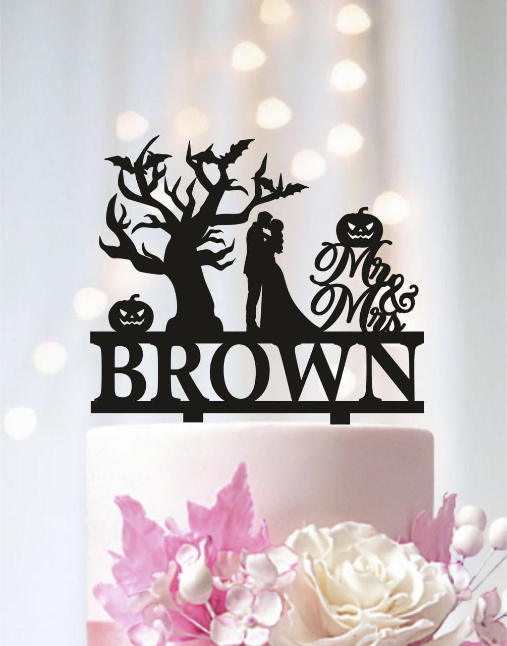 A black silhouette of a bride and groom on a cake topper, with the word "BROWN" below it.