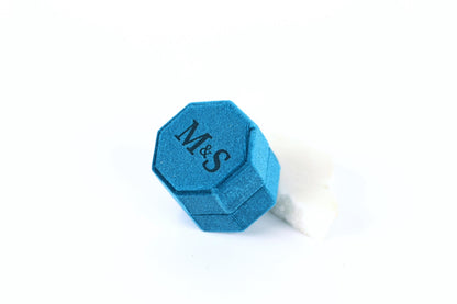 A blue hexagonal box with the letters "M&S" printed on it, sitting on a white surface.