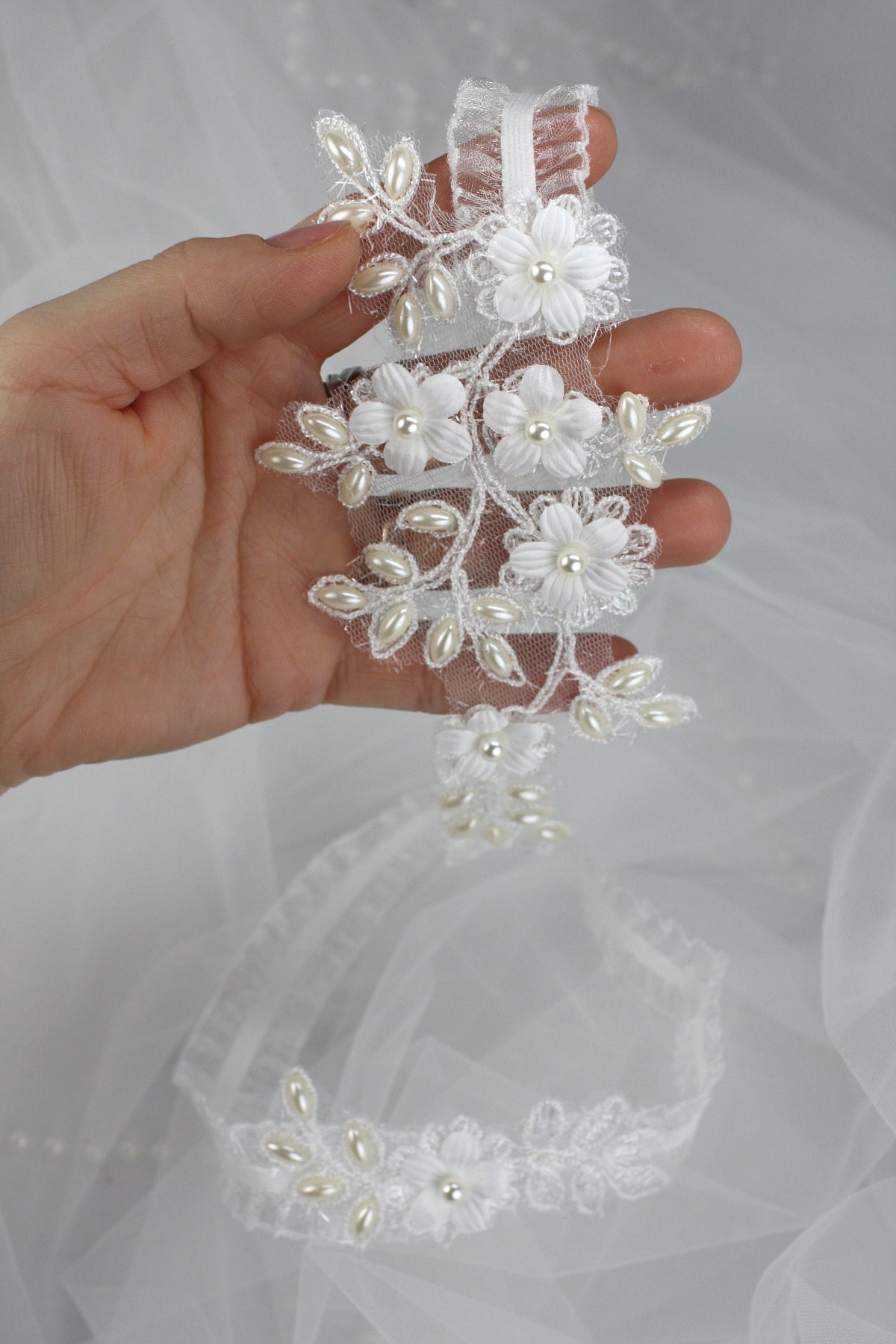 a hand holding a wedding hair comb with flowers on it