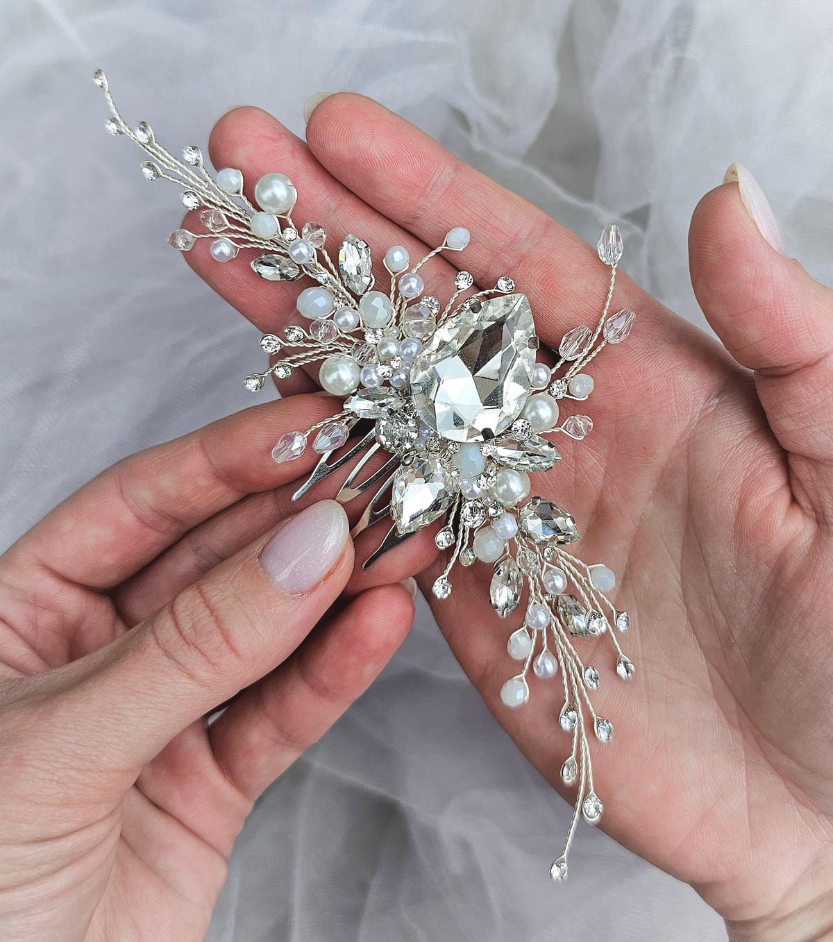 a woman is holding a crystal and pearl brooch