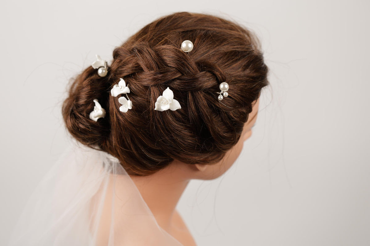 A close-up of a woman's head with her hair styled in an intricate updo, adorned with small white flowers.
