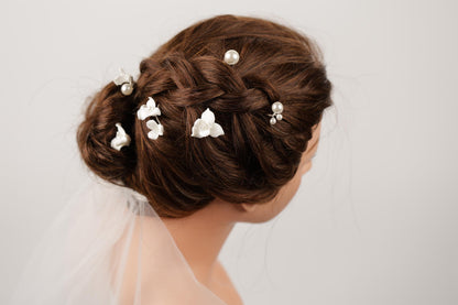 A close-up of a woman's head with her hair styled in an intricate updo, adorned with small white flowers.