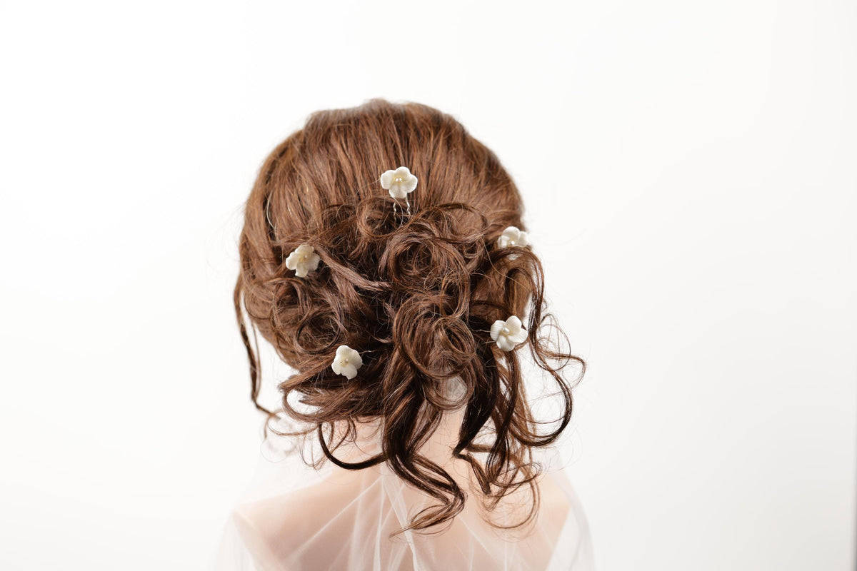 a close-up view of a person's head with their hair styled in a bun, adorned with small white flowers.