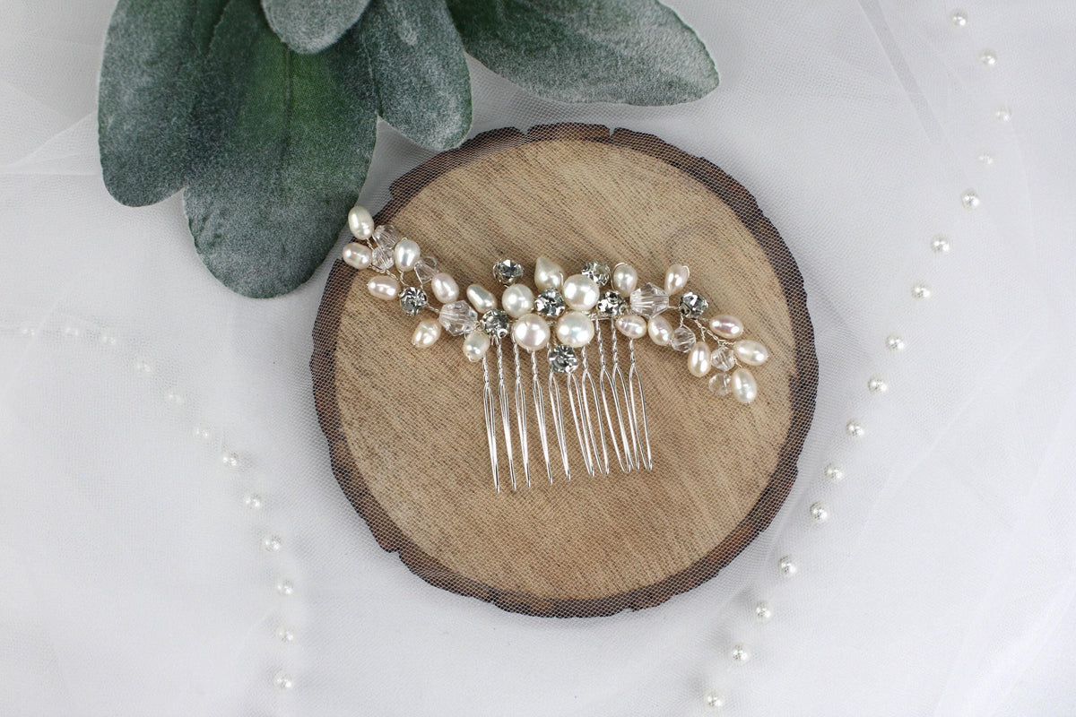 a hair comb with pearls and leaves on a piece of wood
