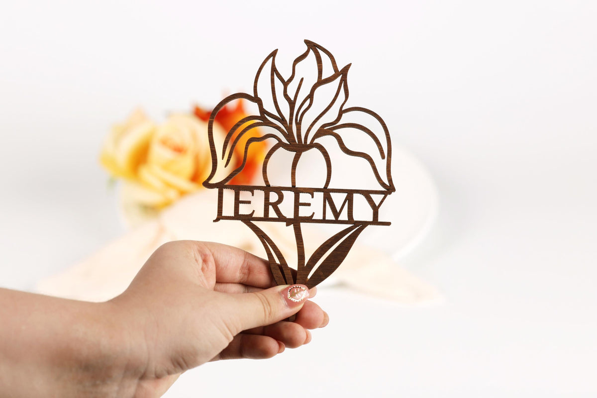 A hand holding a paper cutout of a flower with the word "EREMY" written on it.