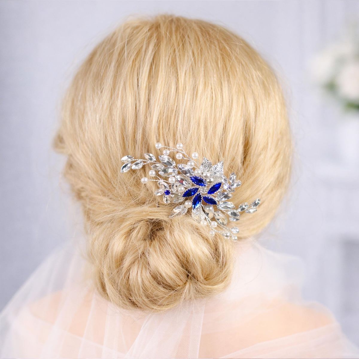 A close-up view of a woman's blonde hair with a decorative hair accessory featuring blue and silver embellishments.