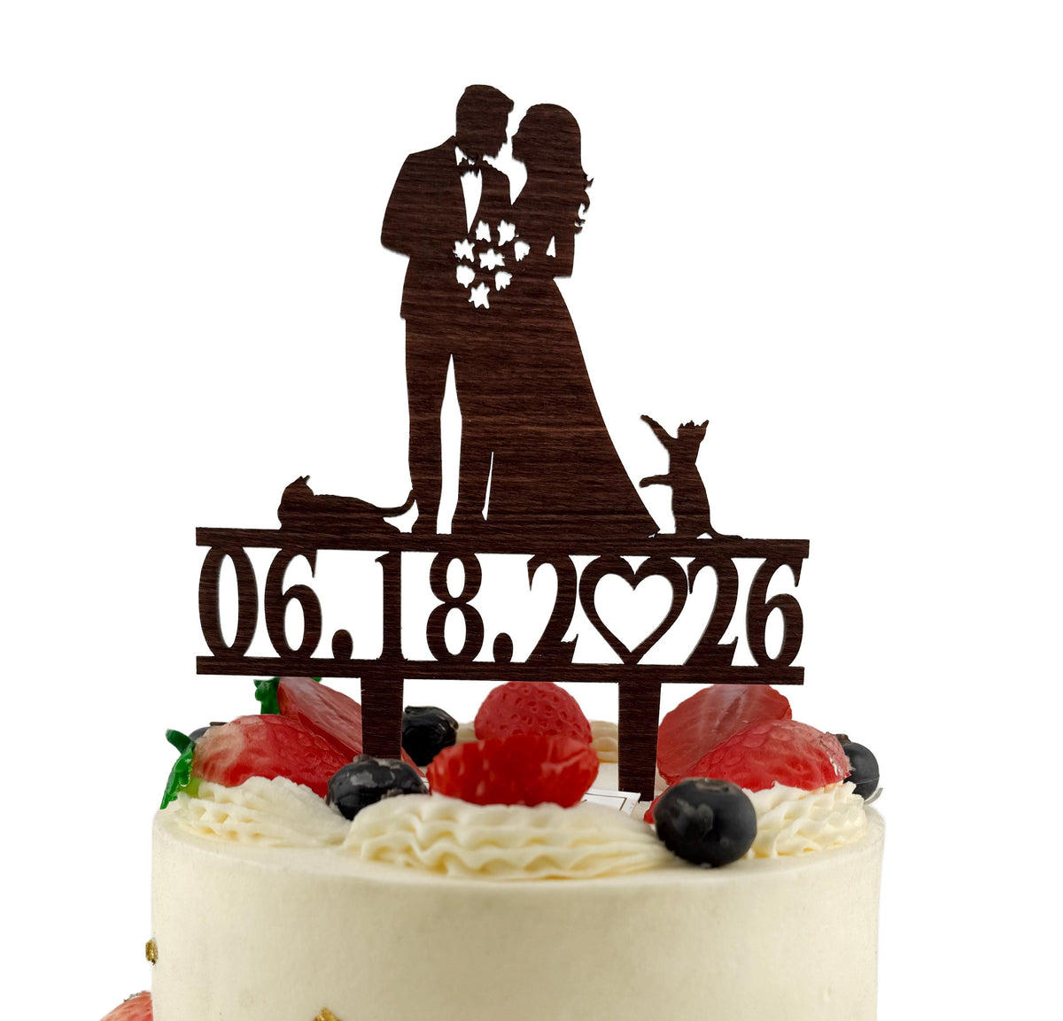 A wooden wedding cake topper with a silhouette of a bride and groom, and the date "06.18.2026" printed on it.