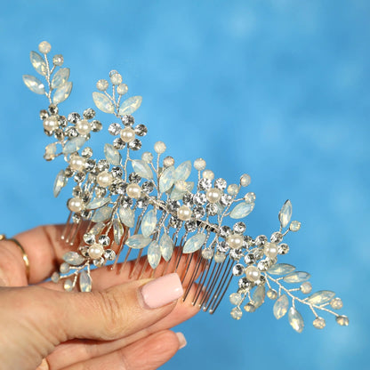 A hand holding a decorative hair accessory with small white and clear gemstones.