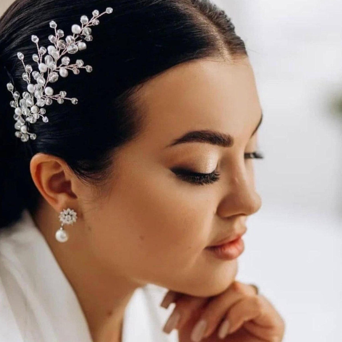 A close-up portrait of a woman with her hair adorned with a decorative hair accessory, showcasing her elegant and poised appearance.