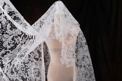 a woman's wedding dress with a white lace shawl