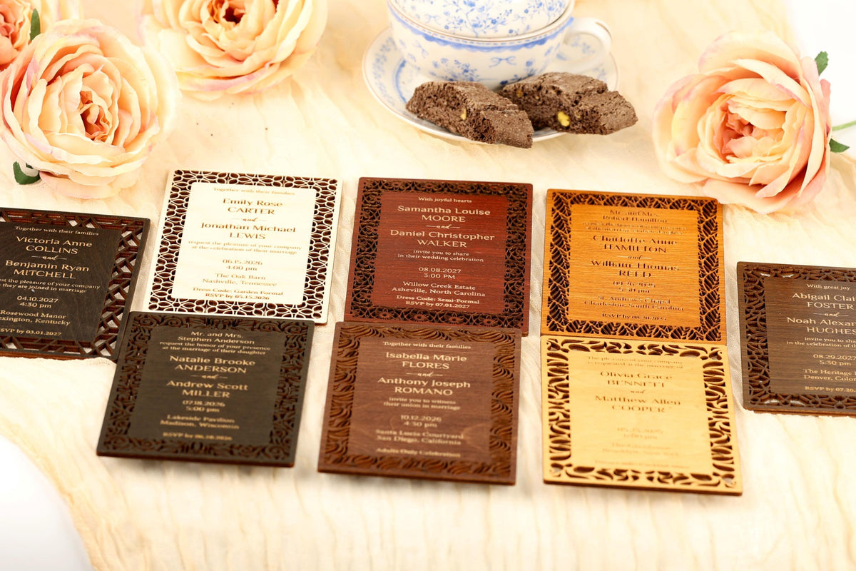 A collection of wedding invitations with various designs and colors, including brown, black, and wooden frames, arranged on a table with pink roses and a teacup.
