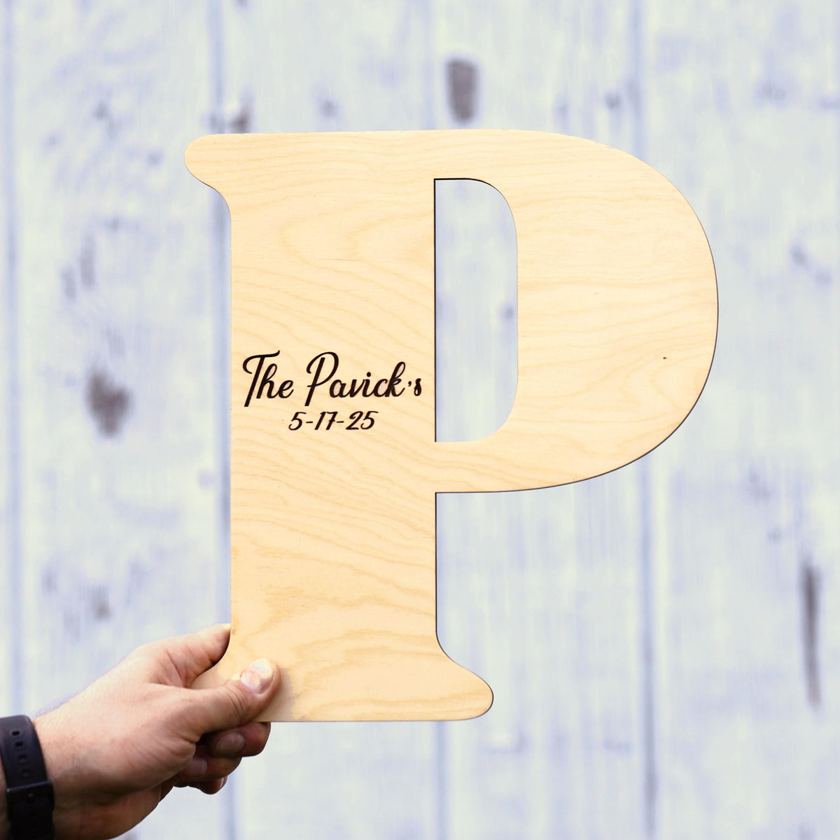 a person holding up a wooden sign with the letter p on it