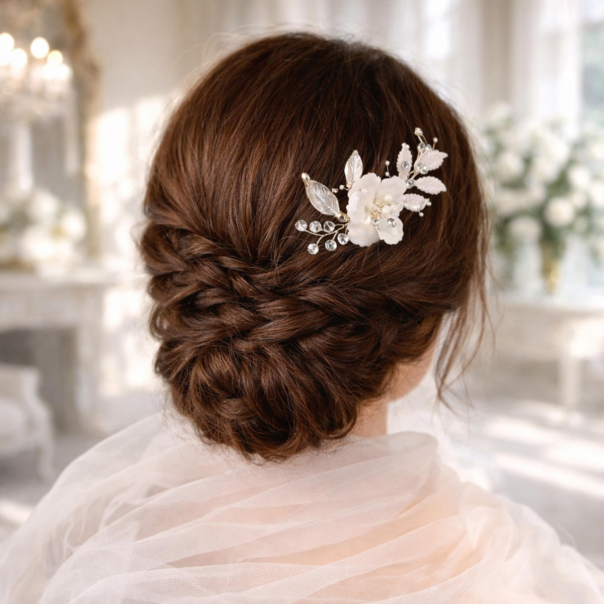 a woman's back view with her hair styled in a bun, adorned with a decorative hair accessory featuring white flowers and leaves.