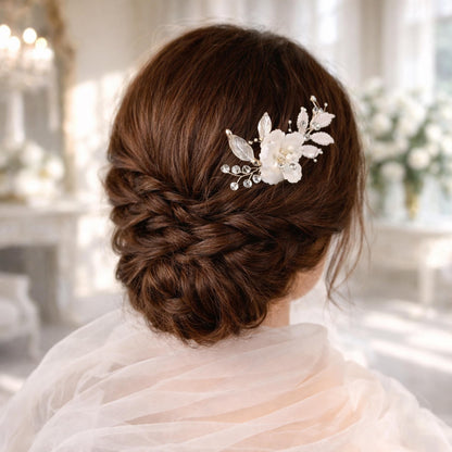 a woman's back view with her hair styled in a bun, adorned with a decorative hair accessory featuring white flowers and leaves.