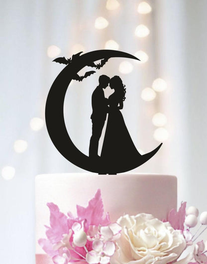 A silhouette of a couple embracing under a crescent moon, with bats flying above them, is the central focus of the image.