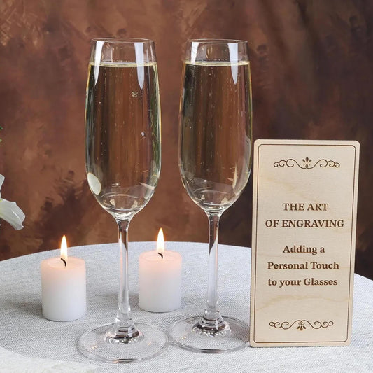 two champagne flutes filled with champagne, placed on a table with a sign that reads "The Art of Engraving: Adding a Personal Touch to your Glasses".