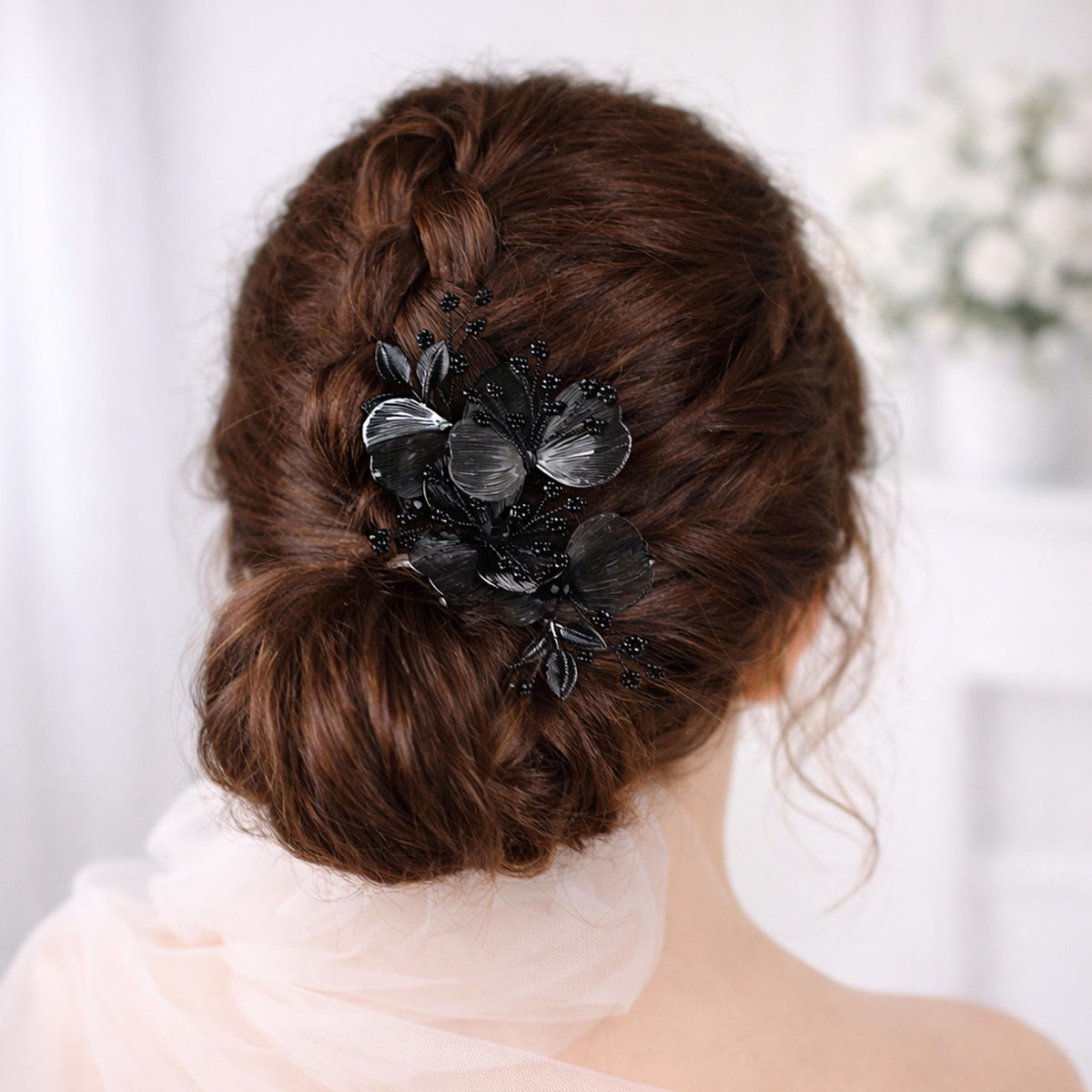 a woman's back view with her hair styled in a bun, adorned with a decorative hair accessory featuring black flowers.