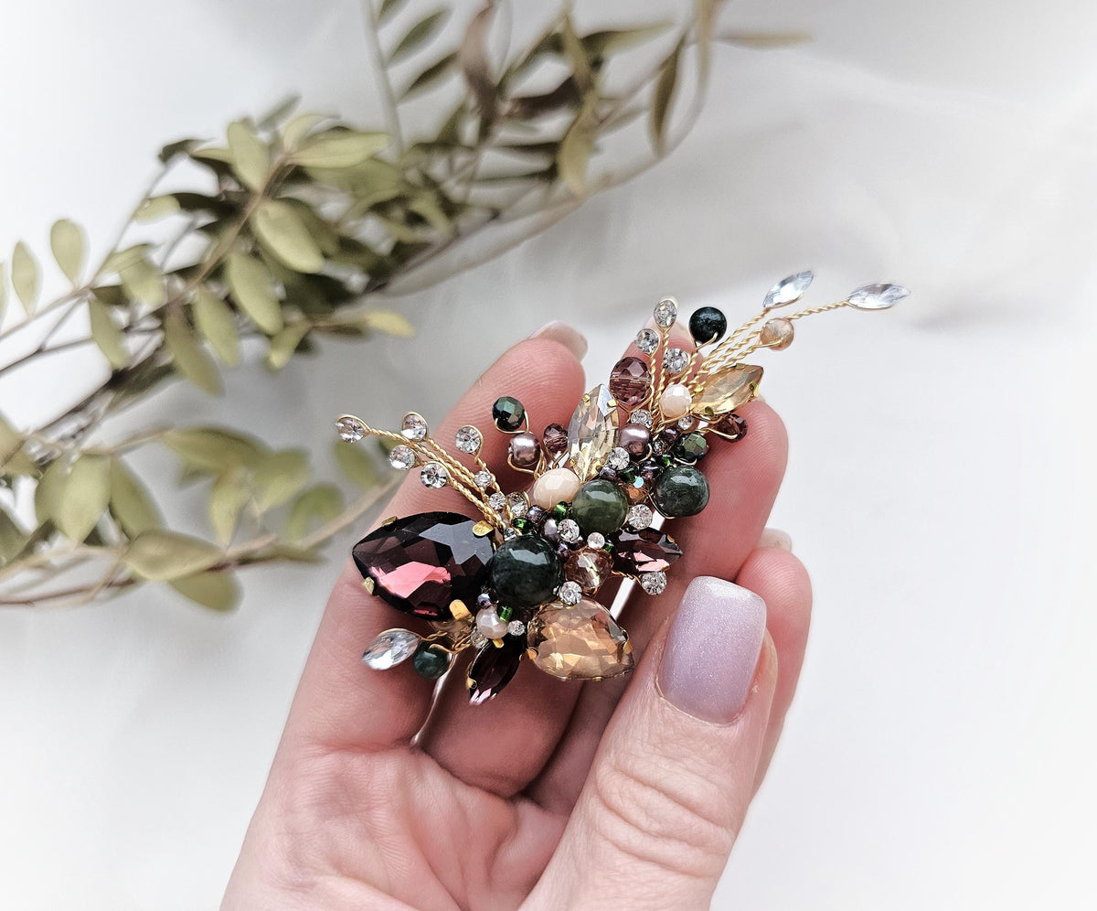 a person holding a flower brooch in their hand