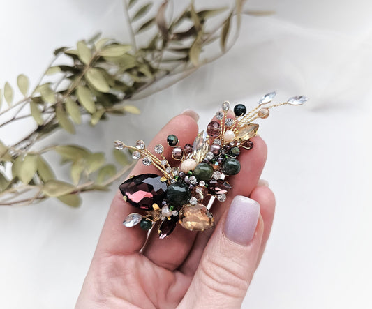 a person holding a flower brooch in their hand