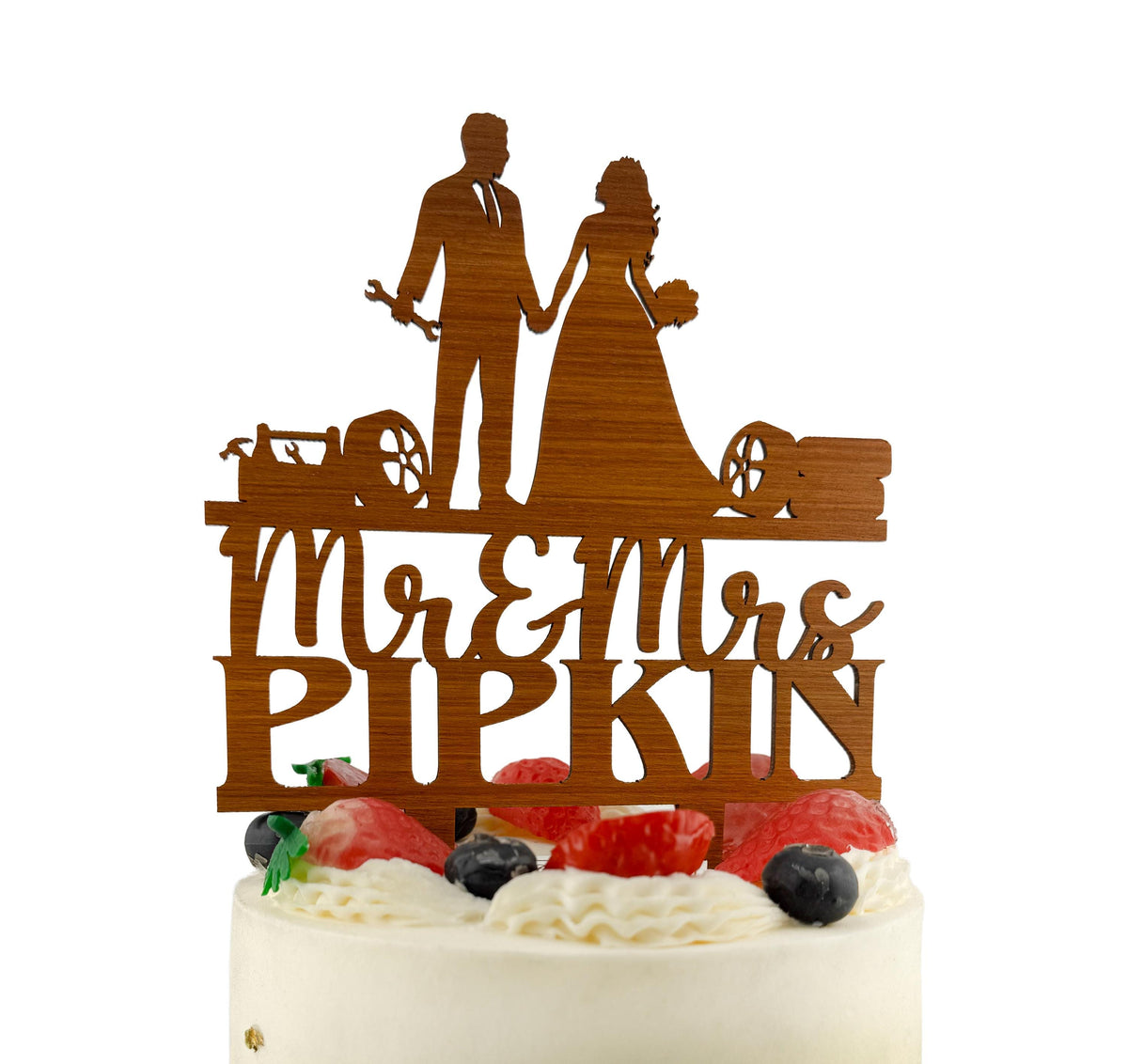 A wooden wedding cake topper with the names 'Mr & Mrs PIPKIN' carved into it.