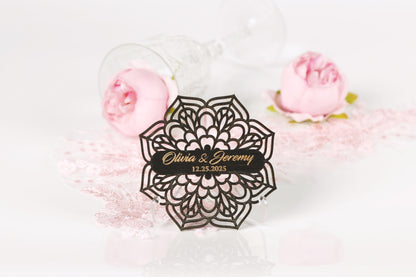 A black ornate wedding card with the names "Olivia & Jeremy" and the date "12.25.2025" is displayed in the center of the image, surrounded by pink roses and a wine glass.
