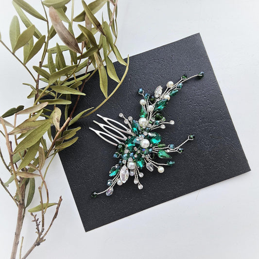 a green and white brooch sitting on top of a black card