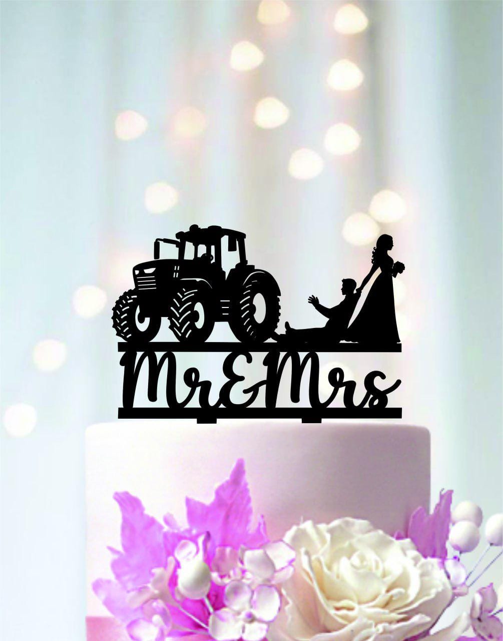 A black silhouette of a tractor and a bride and groom on a cake topper, with the words "Mr & Mrs" written below.
