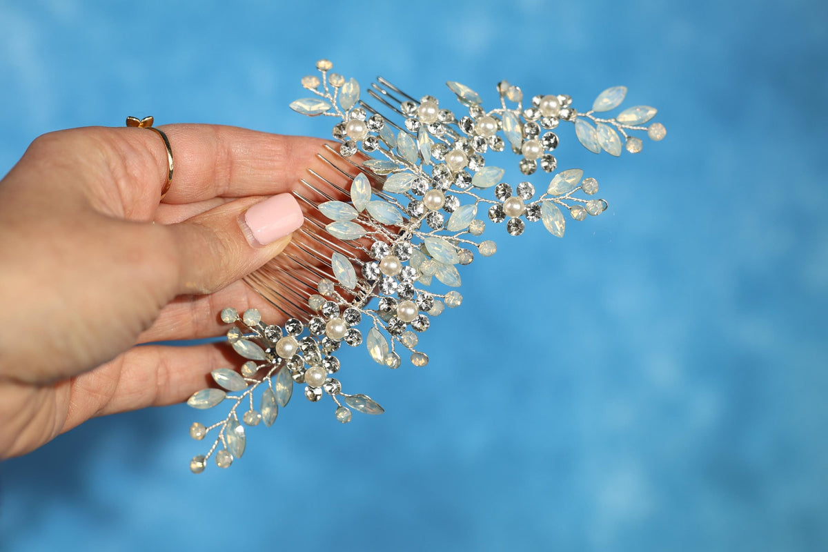 A hand holding a decorative hair accessory with a blue background.