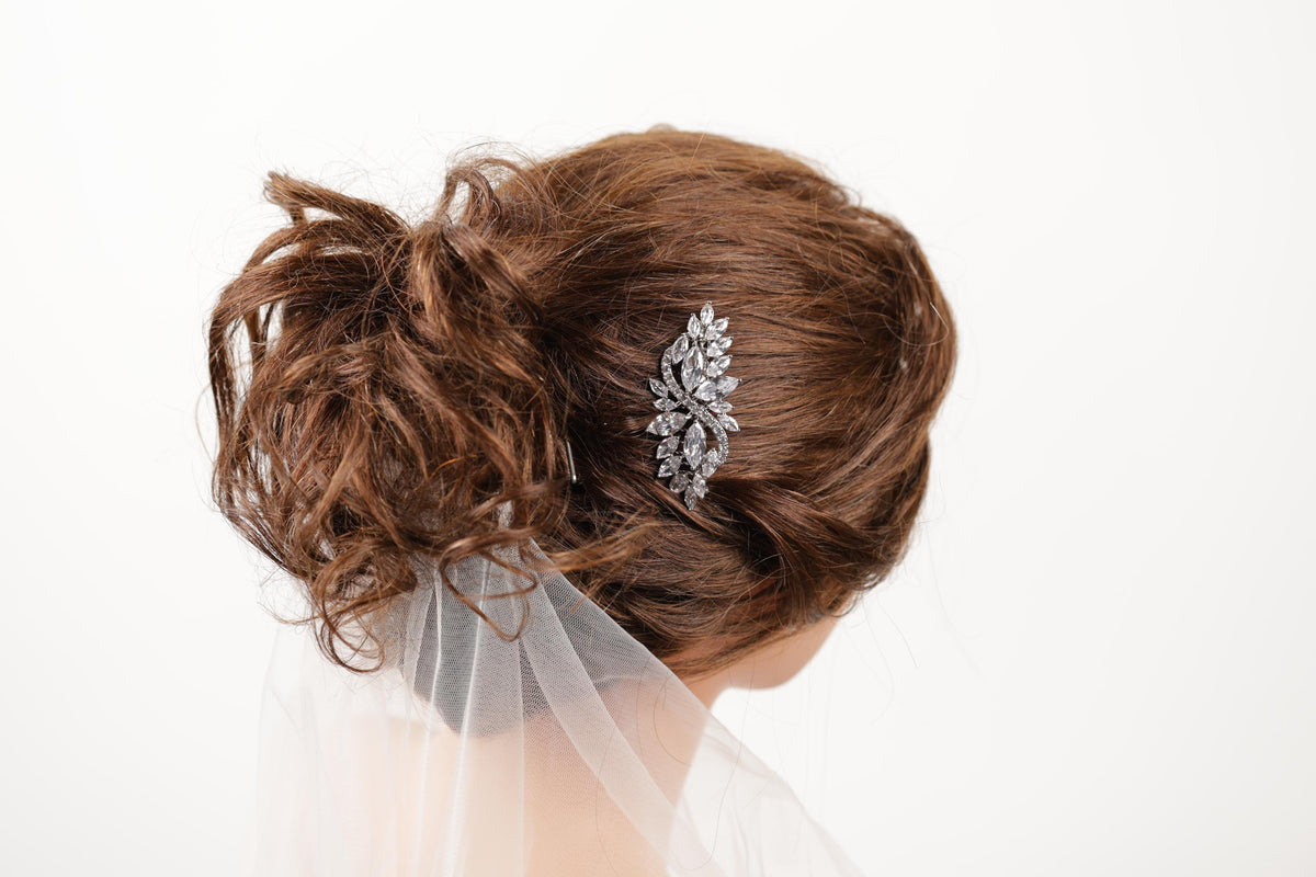 a close-up view of a woman's hair, with a decorative hair accessory, possibly a veil or headpiece, visible in the back.