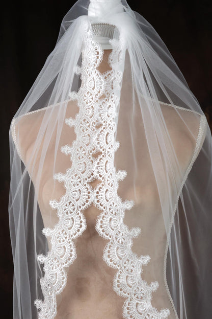 A mannequin wearing a white wedding veil with a delicate lace trim.
