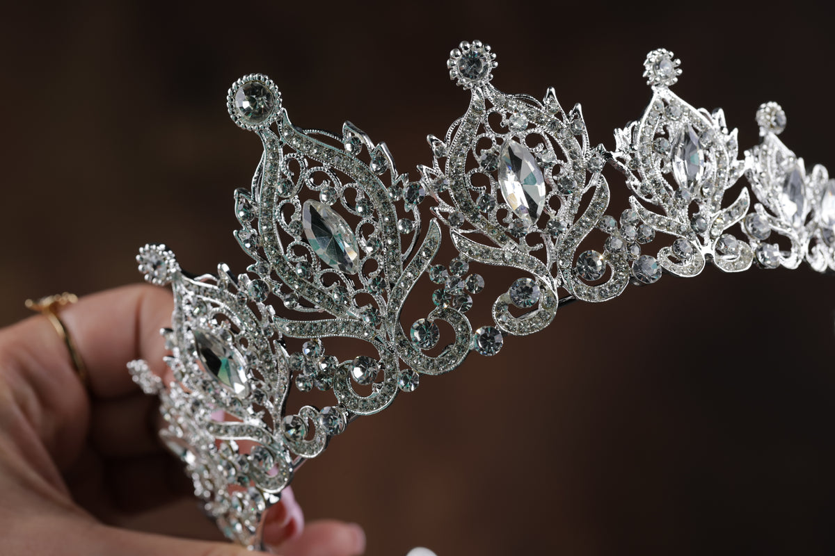 A close-up view of a sparkling silver tiara with intricate designs and sparkling gemstones.