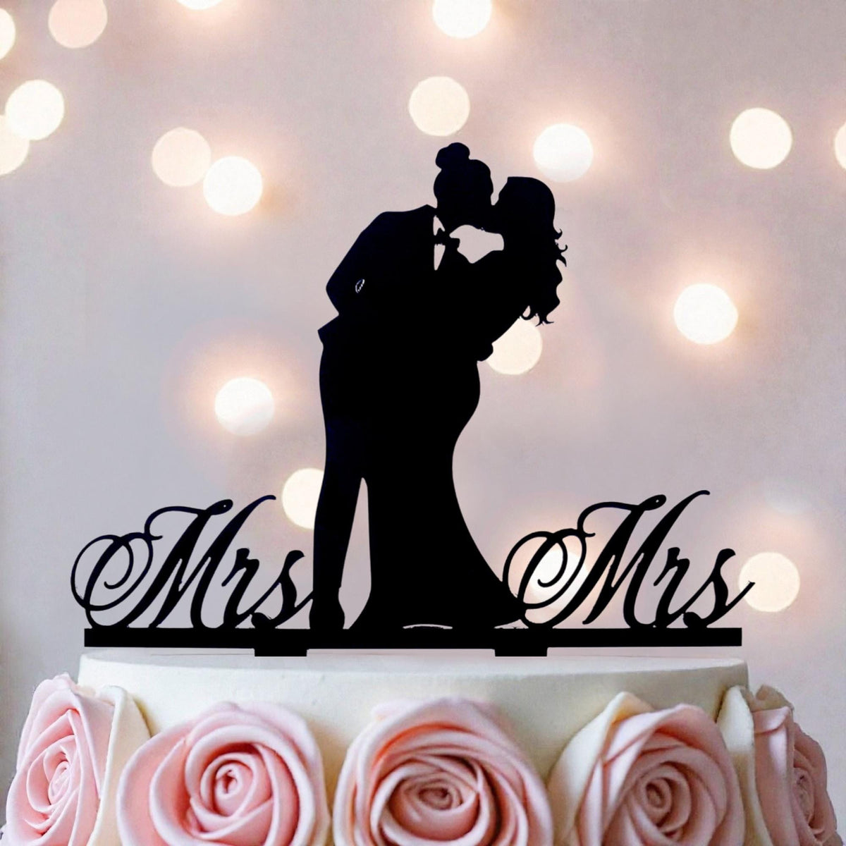 A silhouette of a couple embracing is displayed on top of a wedding cake, with the words "Mrs" and "Mr" written on the cake topper.