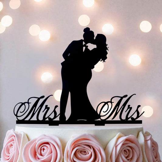 A silhouette of a couple embracing is displayed on top of a wedding cake, with the words "Mrs" and "Mr" written on the cake topper.