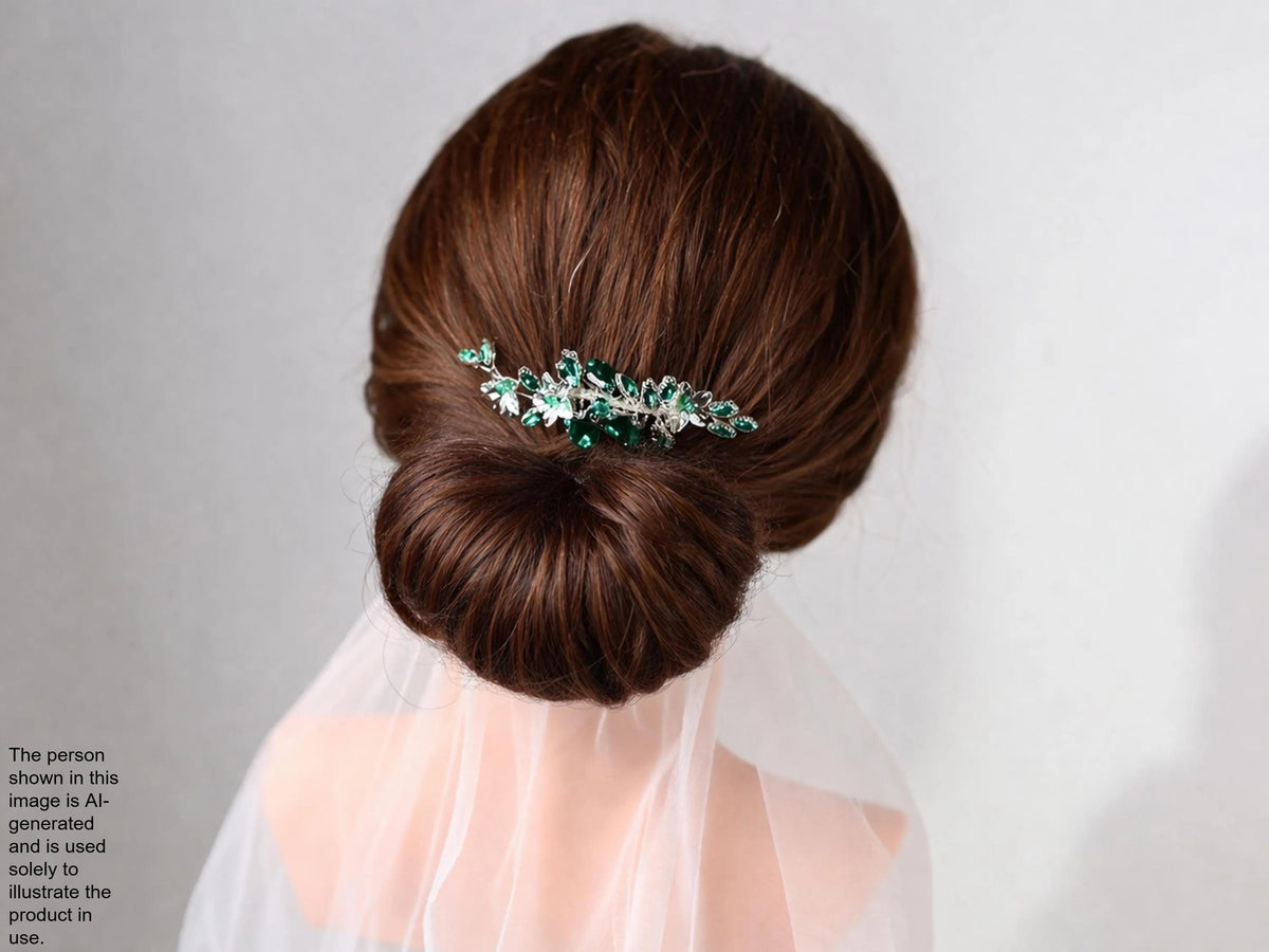 A woman's hair is styled in a bun, with a decorative hair accessory featuring green and silver elements.