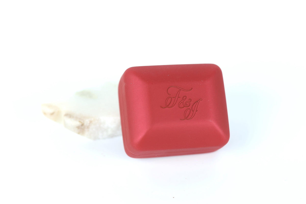 A red, square-shaped object with the text "F&J" embossed on it, placed on a white surface.