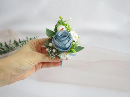 a hand holding a blue and white boutonniere