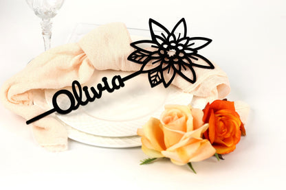 a decorative name tag with the name "Olivia" on a white plate, accompanied by a bouquet of roses.