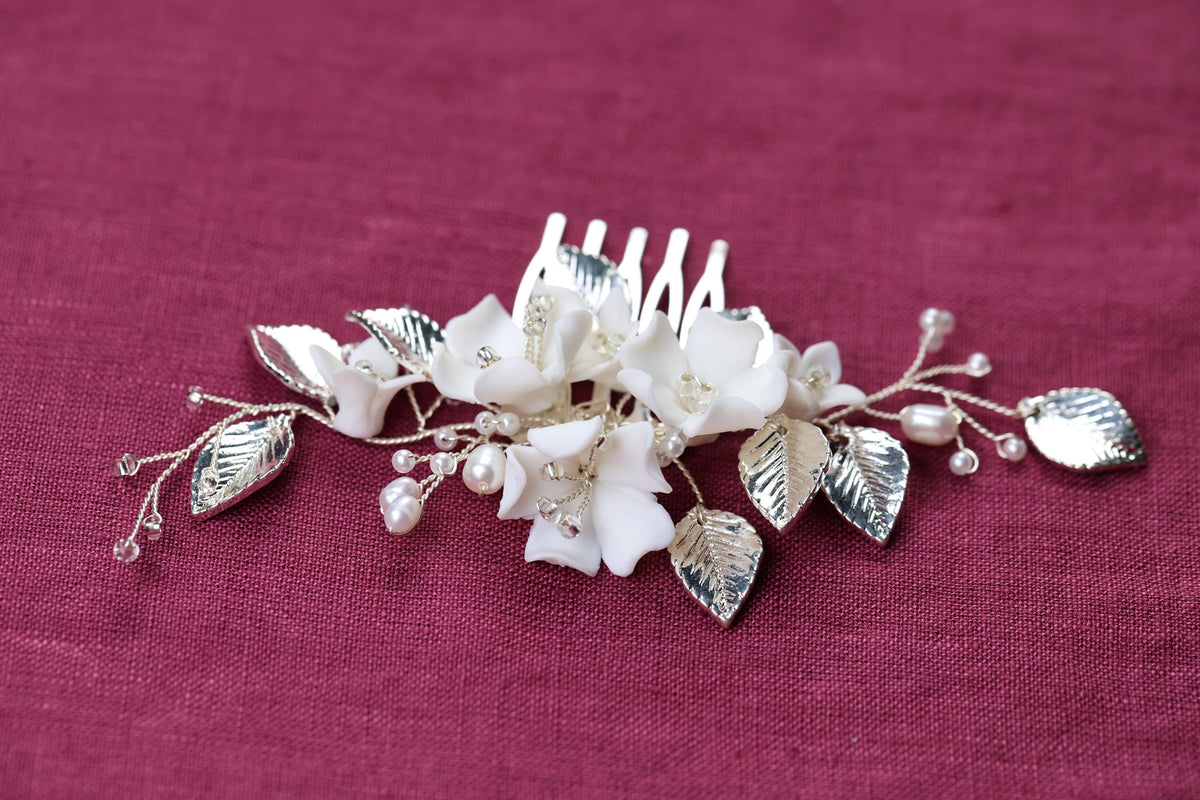 a white flower and leaf comb on a purple cloth