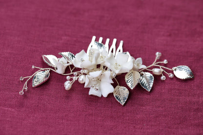 a white flower and leaf comb on a purple cloth