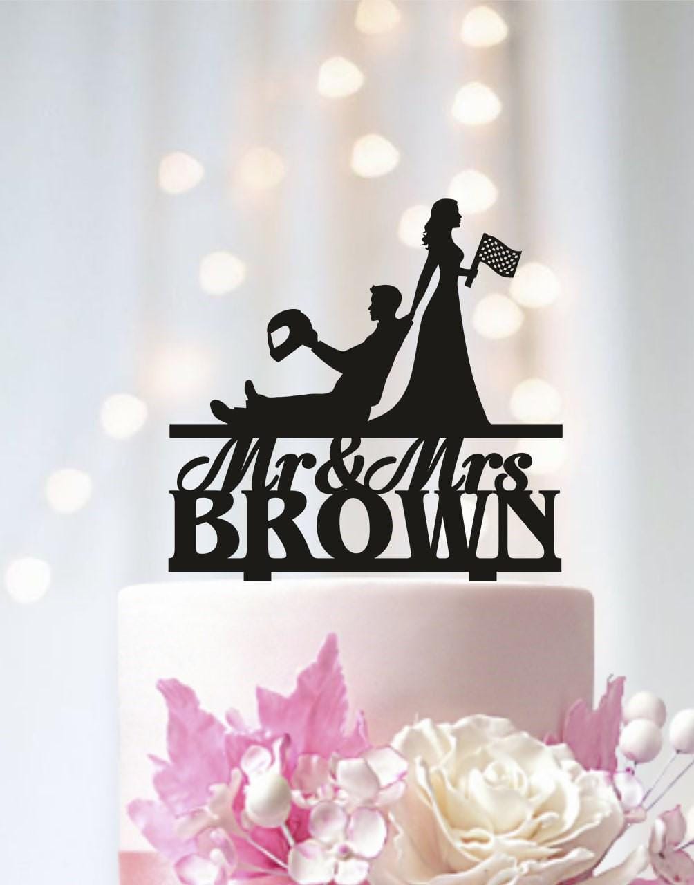 A black silhouette of a man and a woman on a cake topper, with the text "Mr & Mrs Brown" below them.