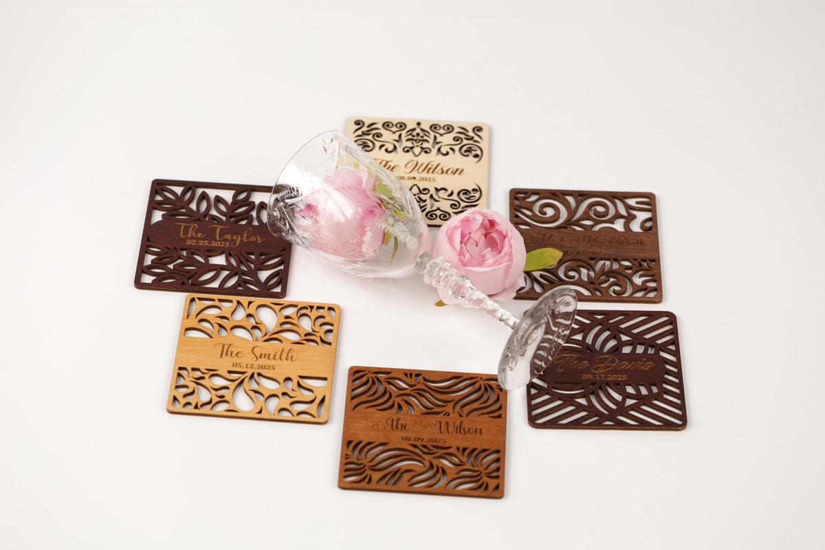 a collection of coasters and a glass of wine, with each item having a personalized name carved into it.