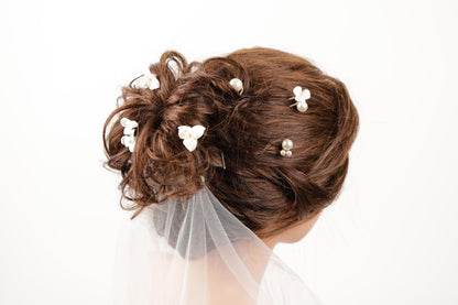 A close-up view of a woman's hair styled in an updo, adorned with small white flowers.