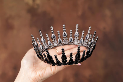 a hand holding a tiara with skulls on it